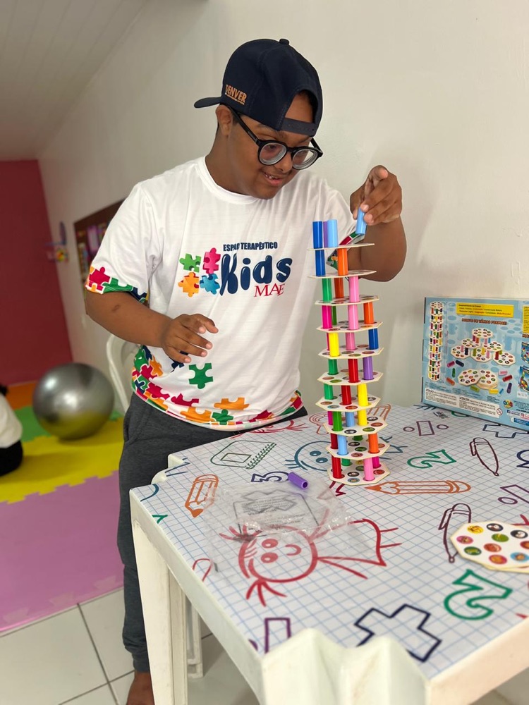 Criança montando torre colorida em atividade de terapia ocupacional